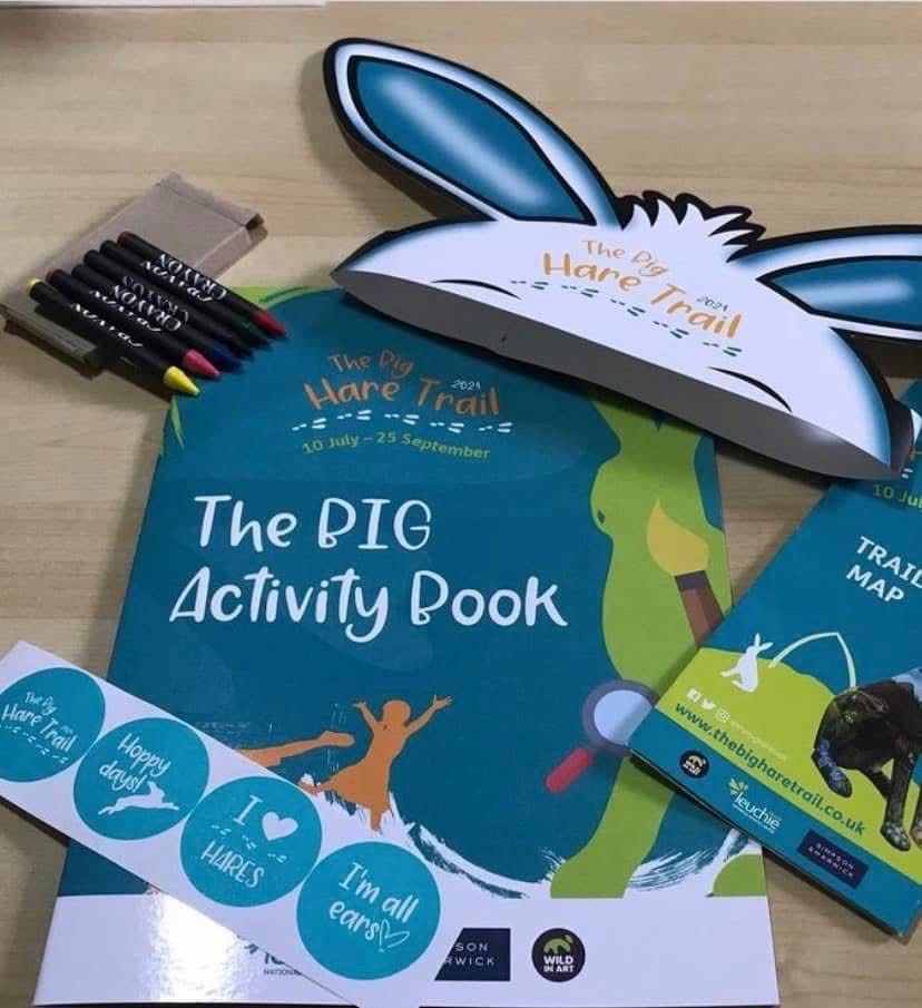 Selection of custom event merchandise for the Big Hare Trail – branded promotional book, t-shirt, tote bag, and gifts produced by Branding Up in Scotland.